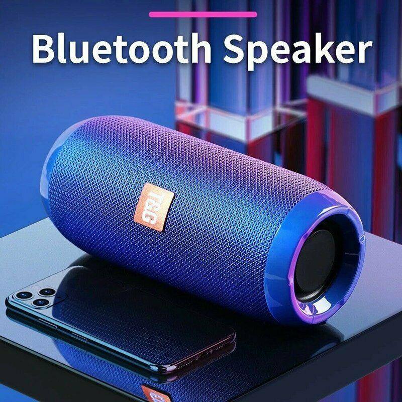 Blue Bluetooth speaker with a smartphone on a reflective surface, against a blurred indoor background.