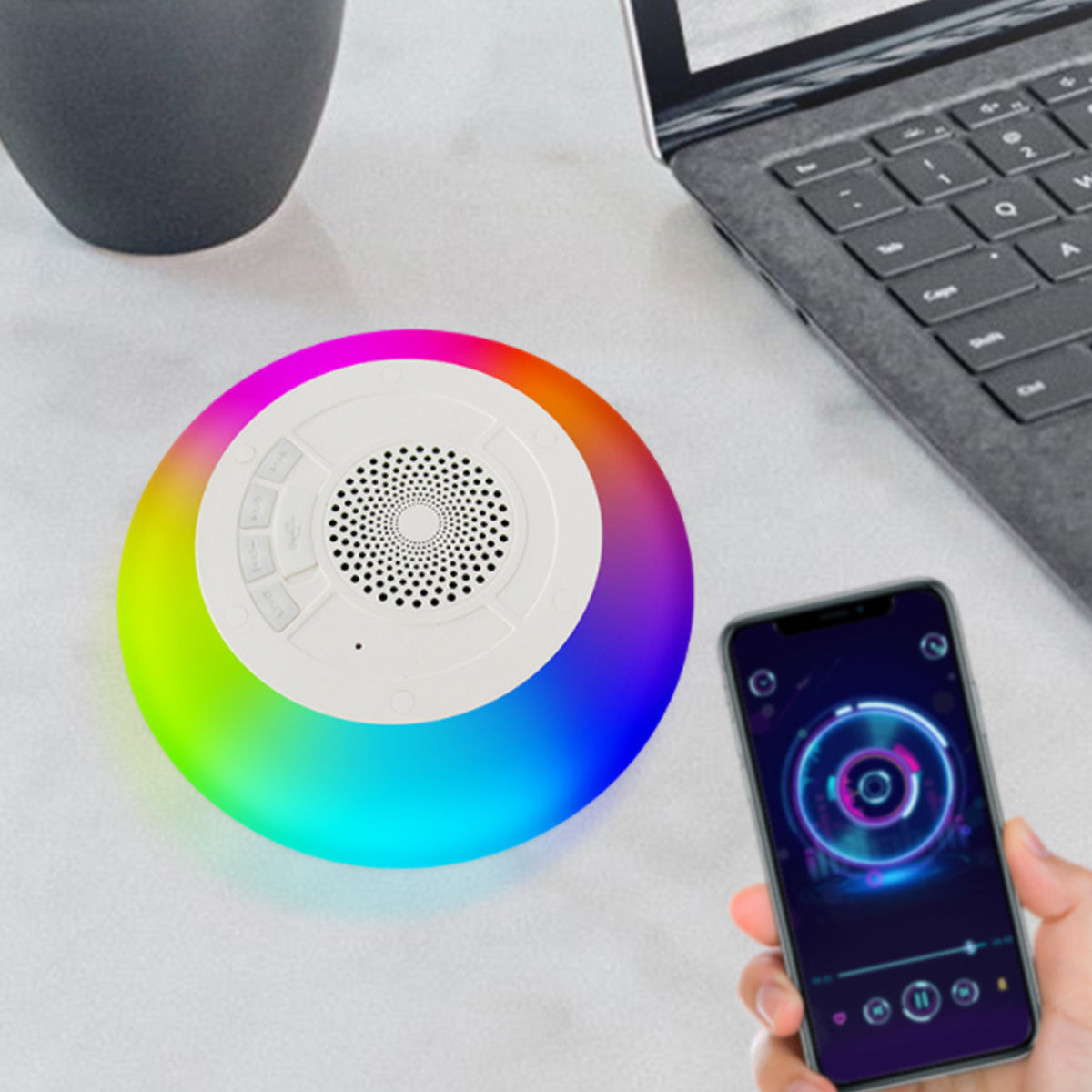 Colorful circular device with a smartphone displaying a similar design, on a light surface with a laptop.
