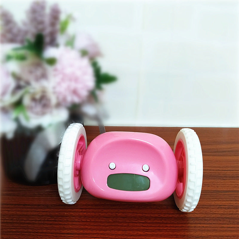 Pink toy car with wheels on a wooden surface with a blurred floral background
