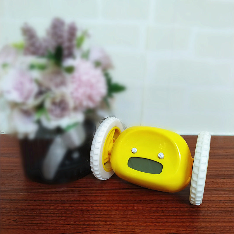Yellow toy car with wheels on a wooden surface, flowers in the background
