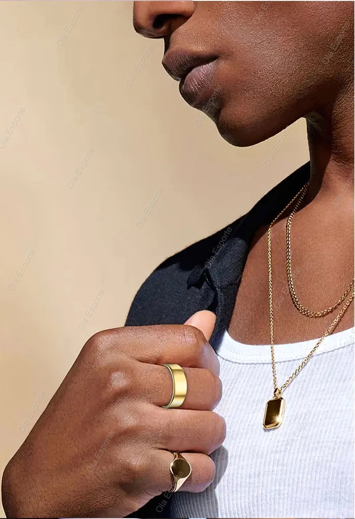 Close-up of a person wearing gold jewelry including rings and necklaces on a beige background