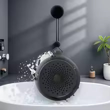 Black showerhead with water flowing into a bathtub against a gray wall.
