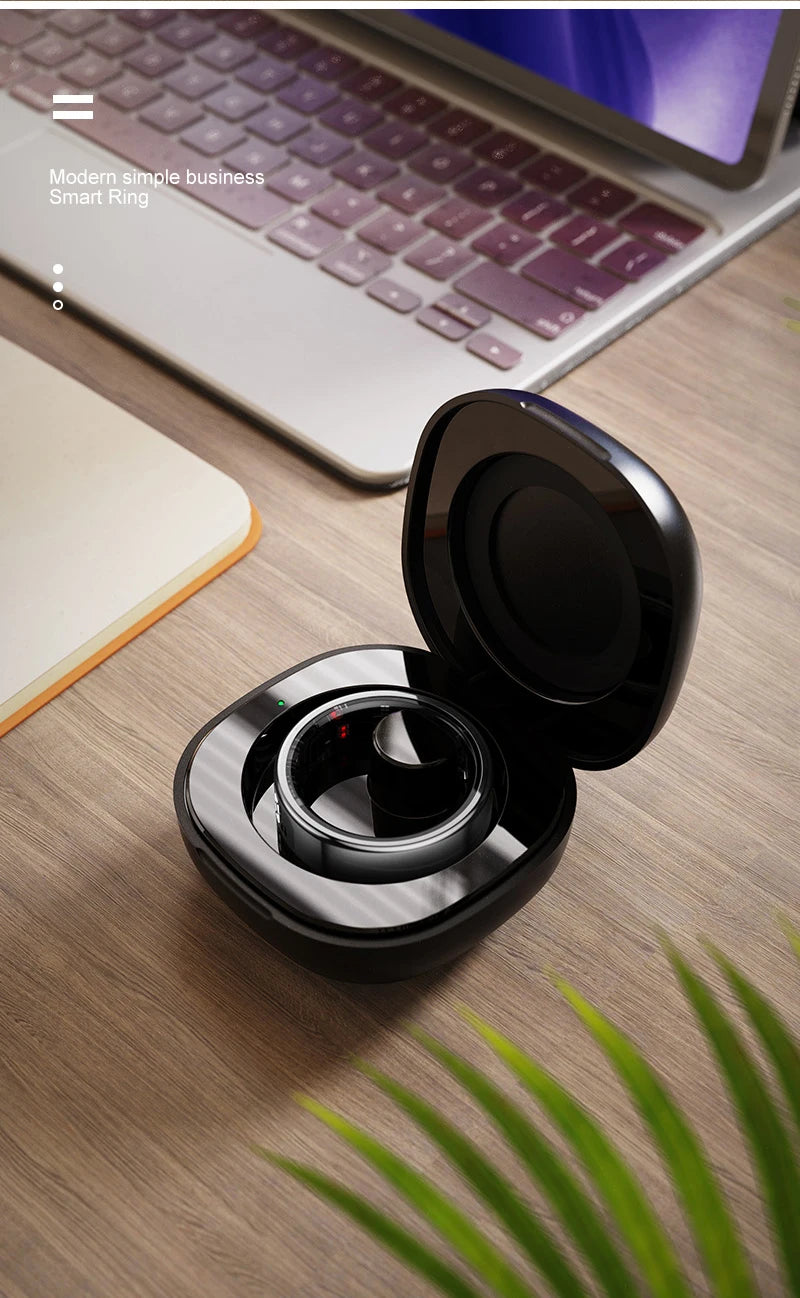 Black wireless earbuds in a charging case on a wooden desk with a laptop in the background.