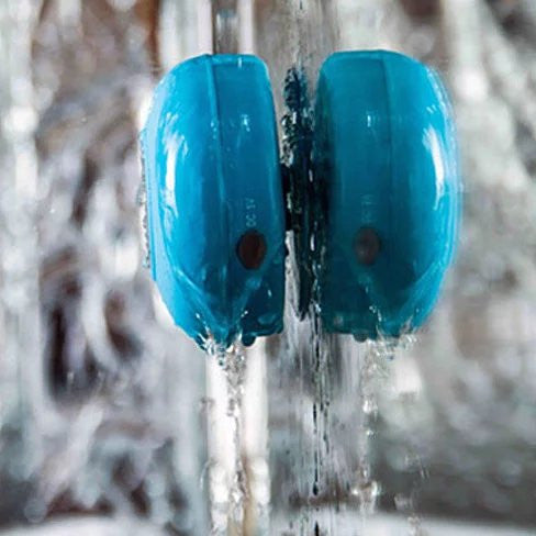 Blue water bottles with water flowing over them against a blurred natural background