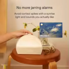 White sleep aid device on a wooden stool with a screen displaying a sunrise scene, surrounded by flowers and glasses.