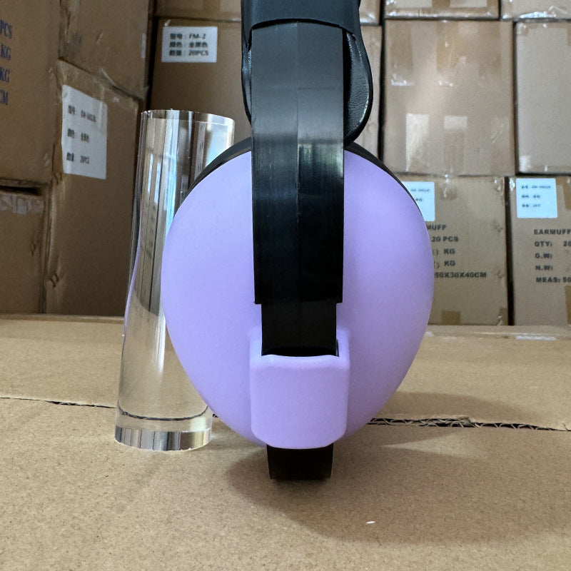 Purple and black spherical object with a clear cylindrical container on a cardboard surface.